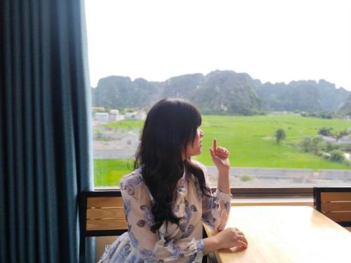 a woman sitting at a table looking out a window at Cherry homestay in Ninh Binh