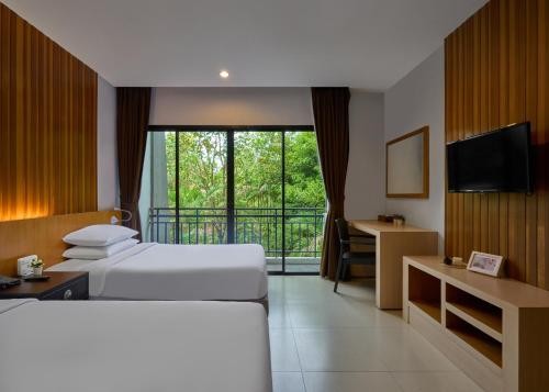 a hotel room with two beds and a television at Nai Yang Beach Resort and Spa in Nai Yang Beach