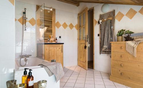 een badkamer met een bad en een wastafel met een spiegel bij CGH Résidences & Spas Le Village De Lessy in Le Grand-Bornand