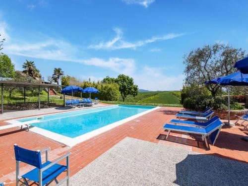 a swimming pool with blue chairs and umbrellas at Peccioli Villa Retreat w Pool in Peccioli