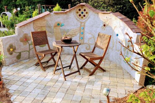 a patio with two chairs and a table with a bird house at Studio Figues et Noix in Orchamps