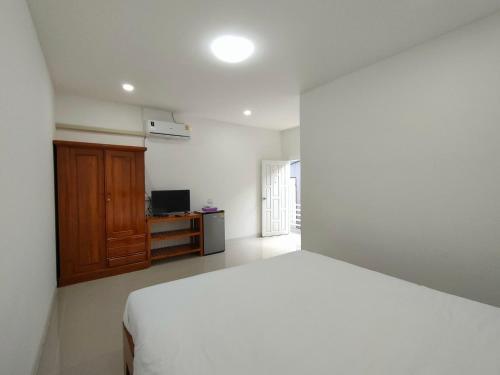 Schlafzimmer mit einem weißen Bett und einem TV in der Unterkunft King Fa House in Mae Sot