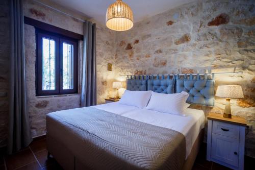 a bedroom with a large bed with a stone wall at Villa Diamante -Seafront Stone Villa for 5 with Stunning Sunset Views By Villa Mana Gers in Amoudi
