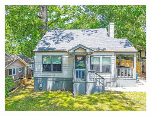 a small white house with a porch on a yard at Lovely 3BR 3BA Home minutes from Airport/Downtown Atlanta in Atlanta