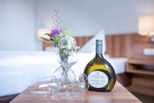 a bottle of wine and a vase of flowers on a table at Weingut Kernwein in Seinsheim
