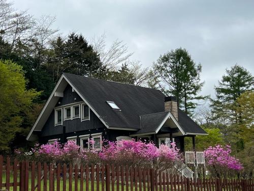 a black house with pink flowers in front of a fence at Juden Fuji168 山中湖湖畔 高級ログハウス 135平米四寝室 in Yamanakako
