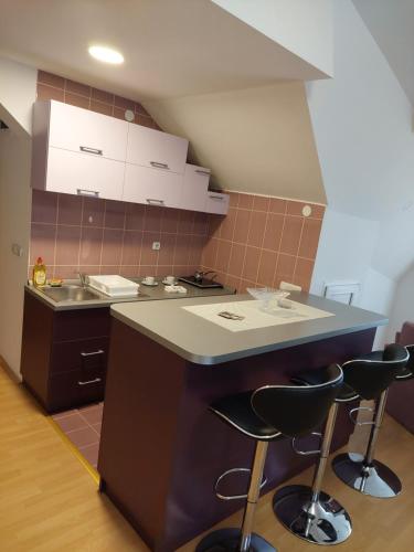 a kitchen with a sink and a counter with stools at Apartmani Milojić in Soko Banja