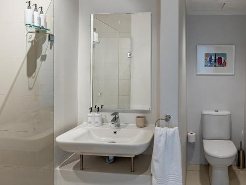 Baño blanco con lavabo y aseo en Blue Views Studio Apartments, en Ciudad del Cabo