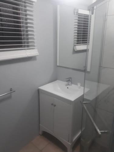 a white bathroom with a sink and a shower at Marina Views Guesthouse in Hartbeespoort