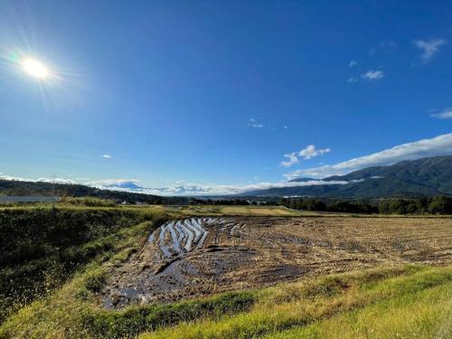 a dirt road in a field with the sun in the sky at HOKUTO SATOYAMA BASE in Hokuto