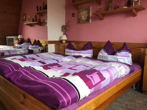 duże łóżko z fioletowo-białą pościelą i poduszkami w obiekcie Bella Vista w Vrchlabi