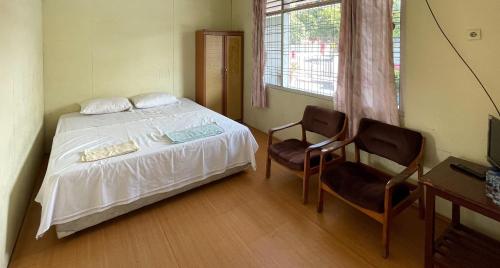 a bedroom with a bed and two chairs at Valencia Homestay Redpartner in Parapat