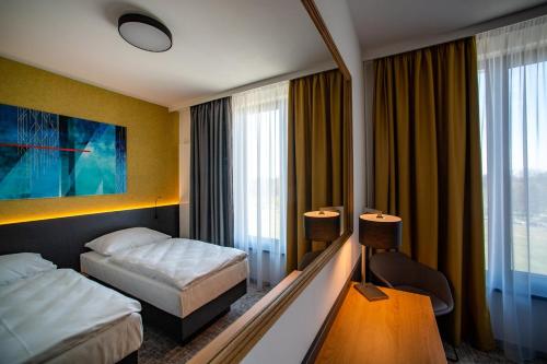 フラデツ・クラーロヴェーにあるEA Congress Hotel Aldisのベッド2台と大きな窓が備わるホテルルームです。