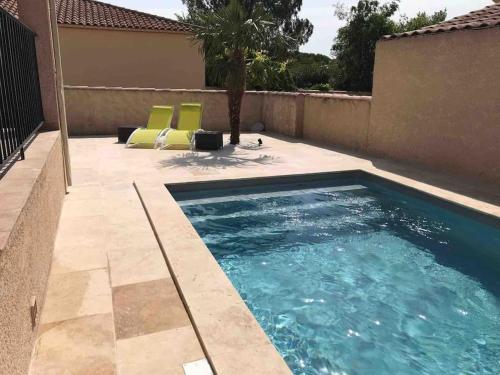 - une piscine avec 2 chaises jaunes à côté d'une maison dans l'établissement Le clos de la cerise - Villa Gilbert, à Châteauneuf-du-Pape