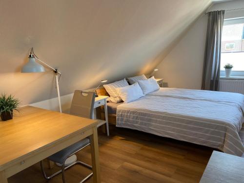 Schlafzimmer mit einem Bett, einem Schreibtisch und einem Tisch in der Unterkunft Ferienwohnung Ausguck in Jever
