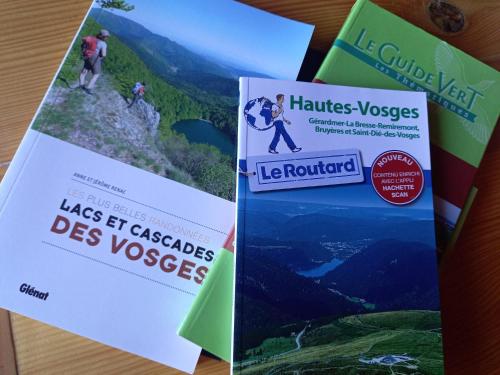 three brochures on a table with people on a mountain at Chalet Typique Vosgien "les Barbotines" in Ventron
