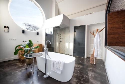 a bathroom with a large white tub and a table at Het Lichthuis in Zandvoort