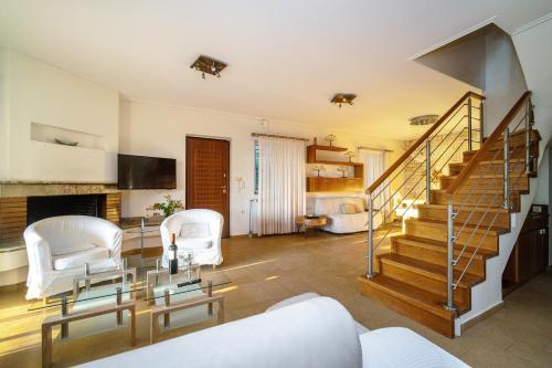 a living room with a staircase and white chairs at VILLA ELENI in Anavissos