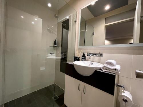 a bathroom with a sink and a glass shower at KOZYGURU | McMahons Point | Amazing Water View Studio + FREE Parking in Sydney