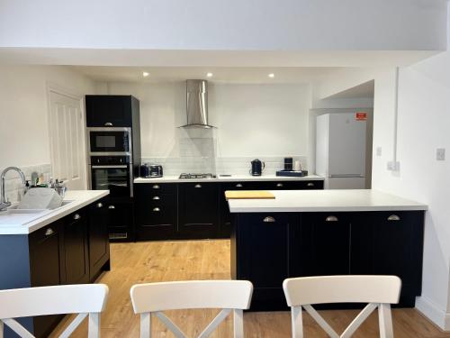 a kitchen with black cabinets and white counter tops at Heathcliff - 5 Bedroom House in Town Centre in Pembrokeshire