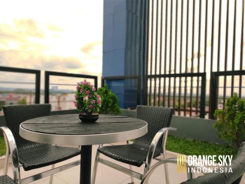 a table with chairs and a potted plant on a balcony at OS Hotel Airport Batam in Batam Center