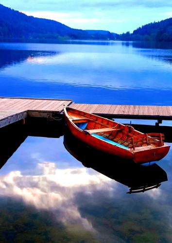 a red boat is parked next to a dock at Chalet Typique Vosgien "les Barbotines" in Ventron