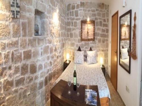 Dormitorio con paredes de piedra, cama y mesa en Apartments Agava & Lucija, en Povlja