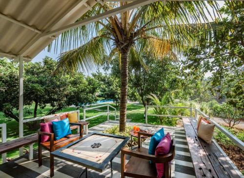 a patio with a table and chairs and a palm tree at SaffronStays Casa Manga, Karjat - pet-friendly pool villa near ND's Film World and Saltt in Karjat