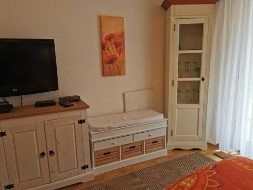 a living room with a tv and a cabinet at Ferienwohnung Grüne Oase in Gößweinstein