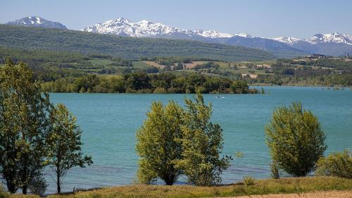 duże jezioro z drzewami i śnieżnymi górami w obiekcie Aux douces nuits de Rivel w mieście Rivel