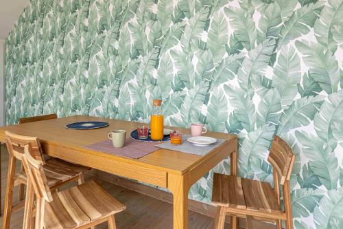 a wooden table with chairs in front of a leafy wallpaper at Residencia Demar in Godella