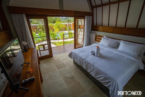 a bedroom with a large bed and a balcony at Driftwood Lombok in Selong Belanak