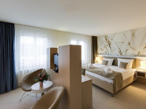 ハノーファーにあるAspria Hannoverの大きなベッドと椅子が備わるホテルルームです。