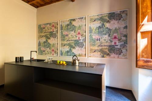 a kitchen with a counter and a wall with paintings at ROMAC Baullari Holiday Apartments in Campo de Fiori in Rome
