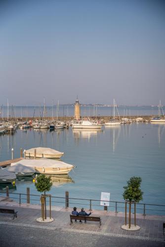 two people sitting on a bench near a marina at Hotel Mayer & Splendid - Wellness e Spa in Desenzano del Garda