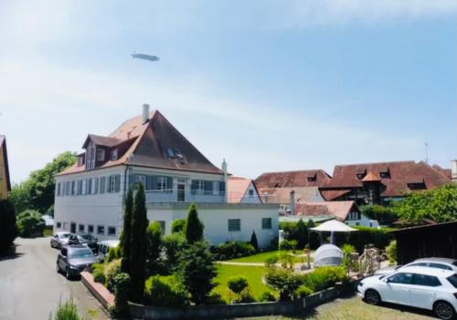 a large white building with cars parked in a parking lot at Hagnau, Irseer Hof in Hagnau