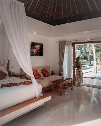 a woman standing in a bedroom with two beds at Jivana Resort in Kuta Lombok