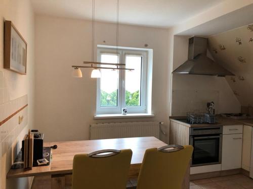 a kitchen with a wooden table and chairs and a window at Ferienwohnungen Lohme in Lohme