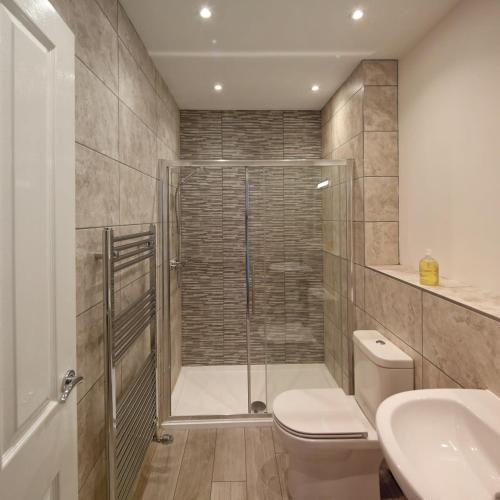 a bathroom with a shower and a toilet and a sink at Torbay Rise sea side villa with family facilities in Torquay