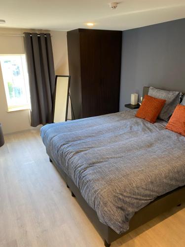 a bedroom with a large bed with orange pillows at De oude es in Bocholt