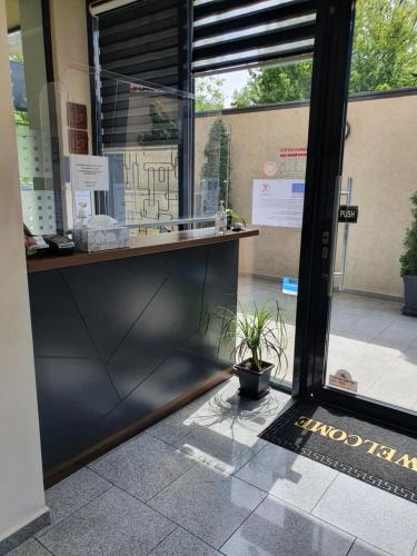 a door to a store with a potted plant in the window at Family Hotel Novel City in Burgas