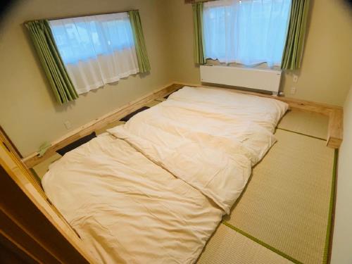 a bed in a room with two windows at TY-Home in Asahikawa