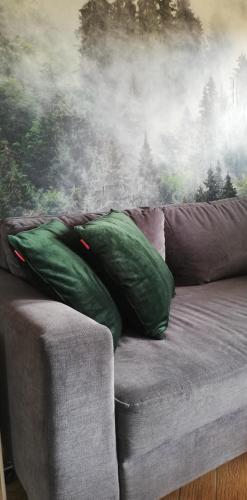 a couch with two green pillows in front of a painting at Domek Chmiel I nad Jeziorem Tarnobrzeskim in Chmielów
