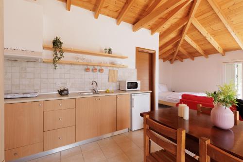 a kitchen with a wooden table and a dining room at The Island Life Apartments by Konnect, Ipsos Beach in Ýpsos