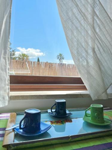 two coffee cups sitting on a table in front of a window at Tra Terra e Mare in Flumini di Quartu