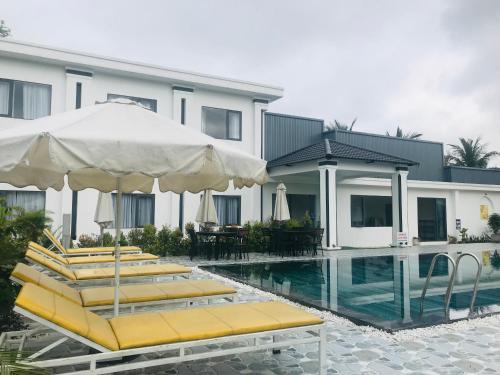 a pool with chairs and umbrellas next to a building at The Dreamers Homestay in Hue
