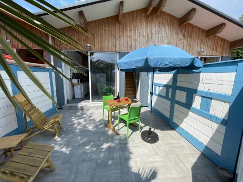 a patio with a table and an umbrella and chairs at Le banc d'Arguin in La Teste-de-Buch