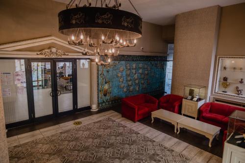 a living room with red chairs and a chandelier at Buyuk Truva Hotel in Canakkale