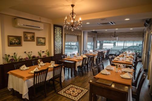 a restaurant with wooden tables and chairs and a chandelier at Buyuk Truva Hotel in Canakkale