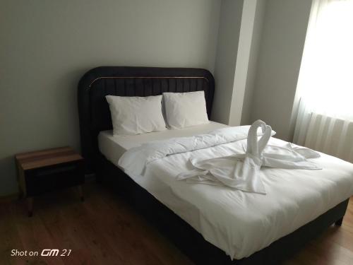 Bett mit schwarzem Rahmen und weißer Bettwäsche in der Unterkunft Siesta Suit in Trabzon